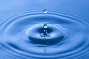 The ripple effects of a water droplet on the surface of water.