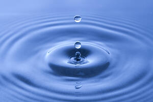 The ripple effects of a water droplet on the surface of water.