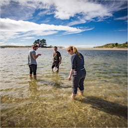 three students standing in a river