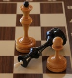 A chess board with the white queen standing and the black king turned on its side