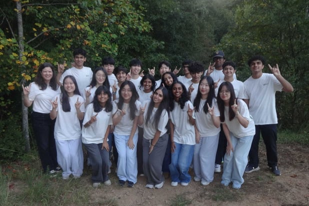 A team of 20 high school students in matching t shirts, along with their teacher.