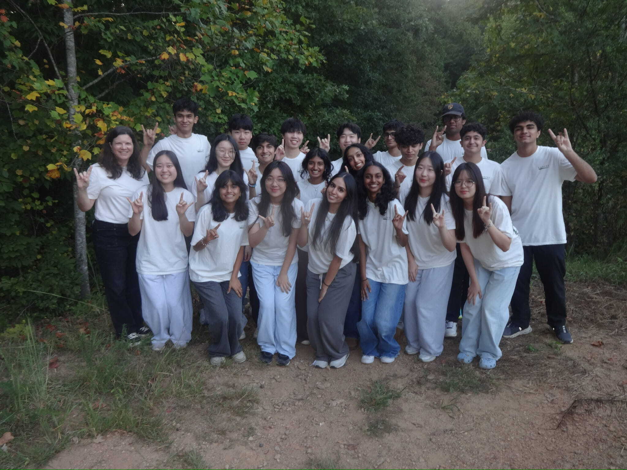A team of 20 high school students in matching t shirts, along with their teacher.